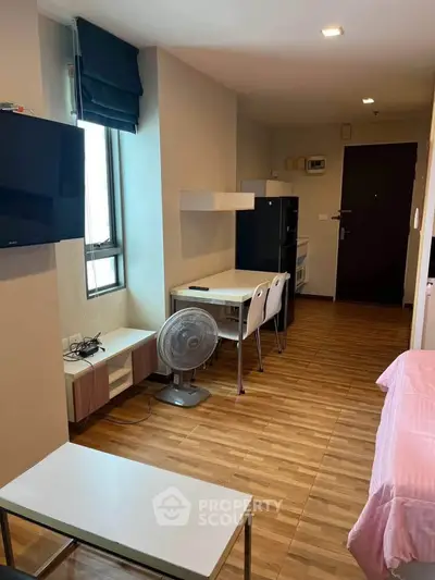 Modern studio apartment with wooden flooring, TV, and compact dining area.