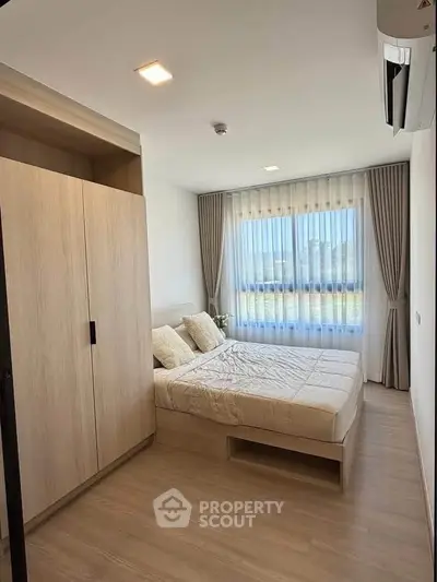 Modern bedroom with natural light, wooden flooring, and stylish curtains in a cozy apartment.