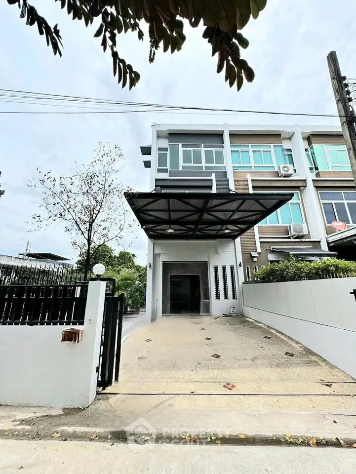 Modern townhouse exterior with driveway and gated entrance, showcasing contemporary architecture.