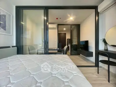 Modern bedroom with glass partition, sleek furniture, and natural light.