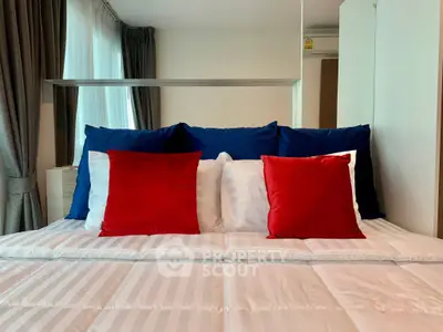 Modern bedroom with stylish red and blue pillows on a neatly made bed, featuring large windows and elegant curtains.