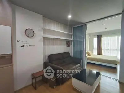Modern living room with cozy sofa and stylish decor leading to a bright bedroom with large windows.