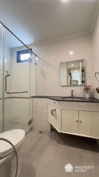 Modern bathroom with glass shower and sleek vanity in stylish apartment.