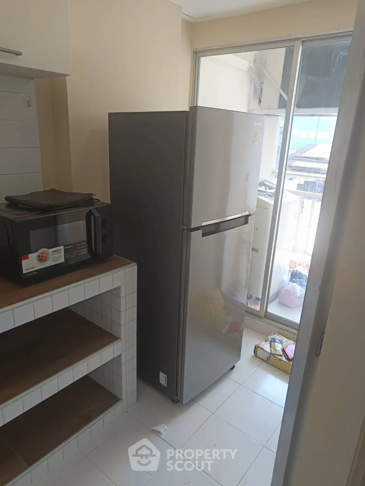 Modern kitchen with sleek fridge and microwave, featuring a balcony view.