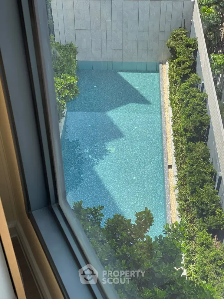 Luxurious apartment view overlooking a serene swimming pool surrounded by lush greenery.