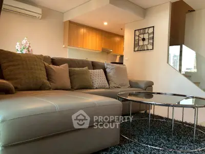 Modern living room with stylish decor and open kitchen layout, featuring a cozy sofa and chic coffee table.