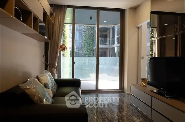 Modern living room with sleek design and large glass doors opening to a balcony.