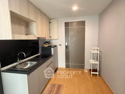 Modern compact kitchen with sleek cabinetry and wood flooring in a cozy apartment.