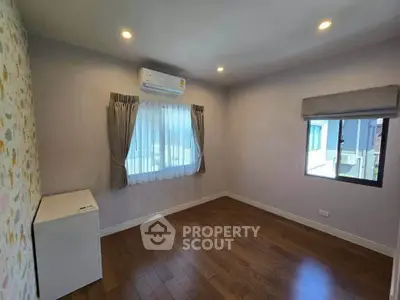 Spacious bedroom with wooden flooring and air conditioning in modern home.