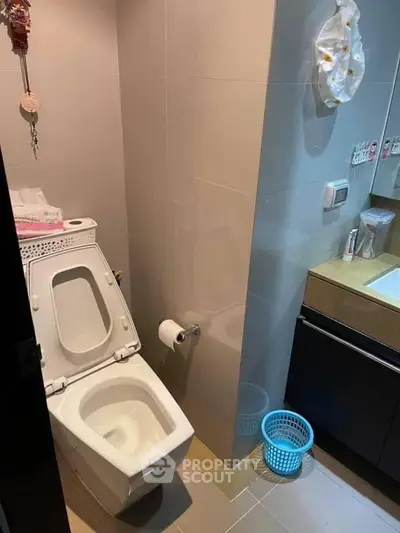 Modern bathroom with sleek design and essential amenities, featuring a toilet and sink area.