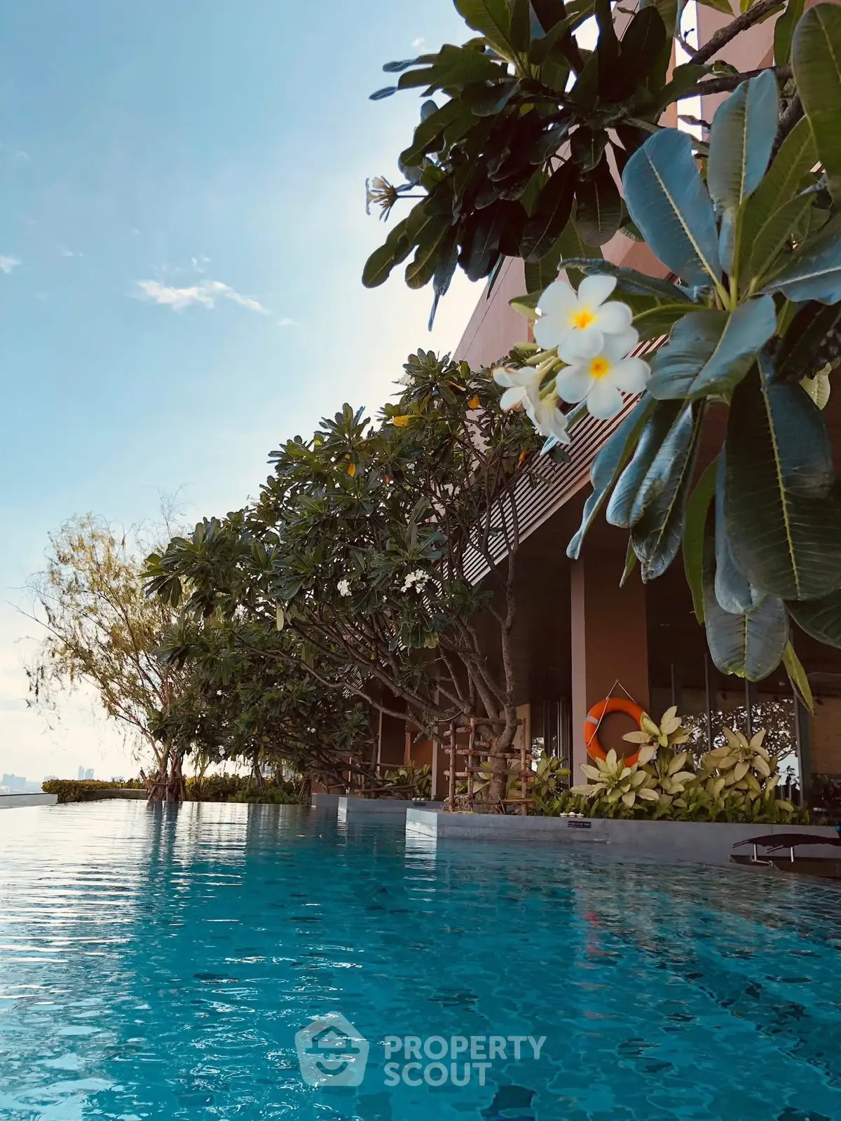 Luxurious infinity pool with lush greenery and serene ambiance in a high-end residential complex.