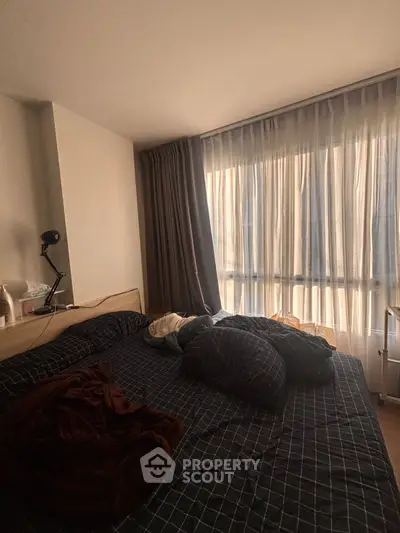 Cozy bedroom with large window and stylish curtains, perfect for natural light lovers.
