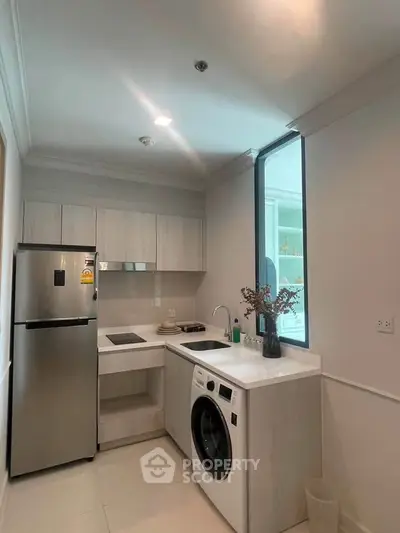 Modern kitchen with sleek appliances and washing machine in compact layout