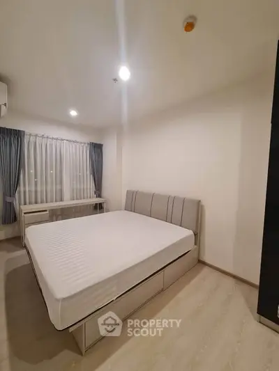 Spacious bedroom with modern decor and large window, perfect for comfort and relaxation.