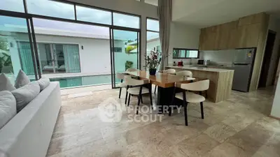 Luxurious open-plan living room with pool view and modern kitchen in a stylish villa.