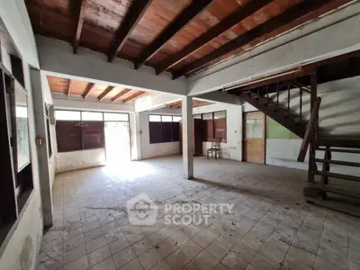 Spacious open-plan interior with rustic wooden ceiling and tiled floor, ideal for renovation.