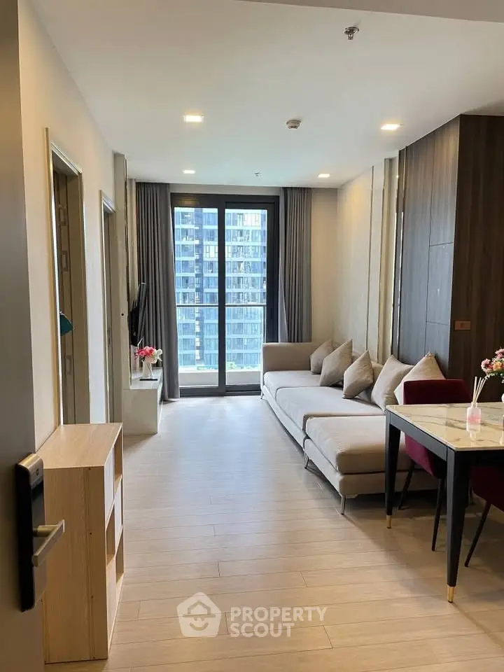 Modern living room with large windows and stylish furniture in a high-rise apartment.