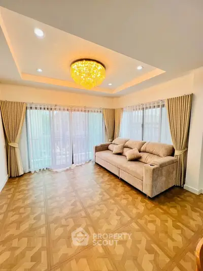 Spacious living room with elegant chandelier and large windows for natural light.
