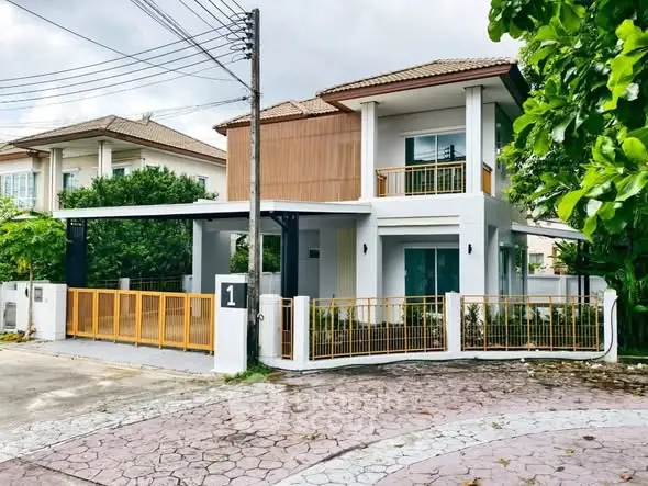 Modern two-story house with balcony and gated entrance in suburban neighborhood.