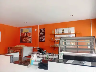 Vibrant orange-themed cafe interior with counter and pizza posters, ideal for a cozy dining experience.