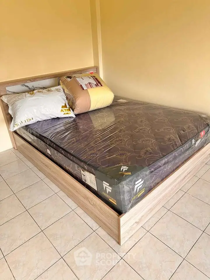 Cozy bedroom with new mattress and wooden bed frame, perfect for restful nights.