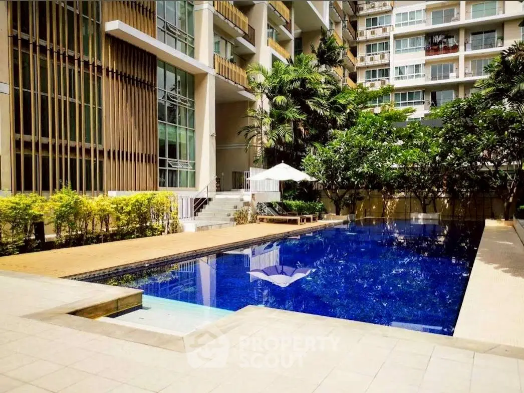Luxurious residential building with a stunning pool and lush greenery, perfect for relaxation and leisure.