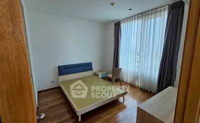 Spacious bedroom with large window and wooden flooring, perfect for natural light lovers.