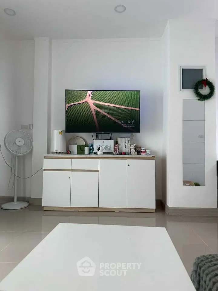 Modern living room with wall-mounted TV and sleek white cabinetry