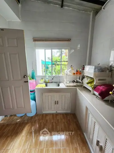 Charming kitchen with natural light, featuring a window view and ample storage space, perfect for cozy home living.