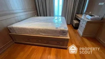 Spacious bedroom with polished hardwood flooring, large windows for ample natural light, and a new mattress still in plastic wrap, ready for the new homeowner.