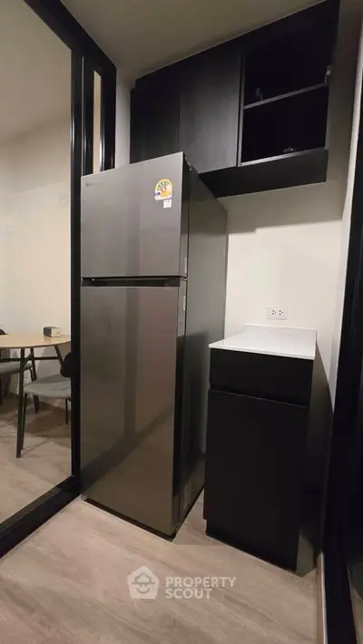 Modern kitchen with sleek fridge and cabinetry in a compact layout