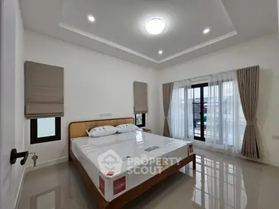 Spacious bedroom with large windows and modern decor in a bright, airy home.