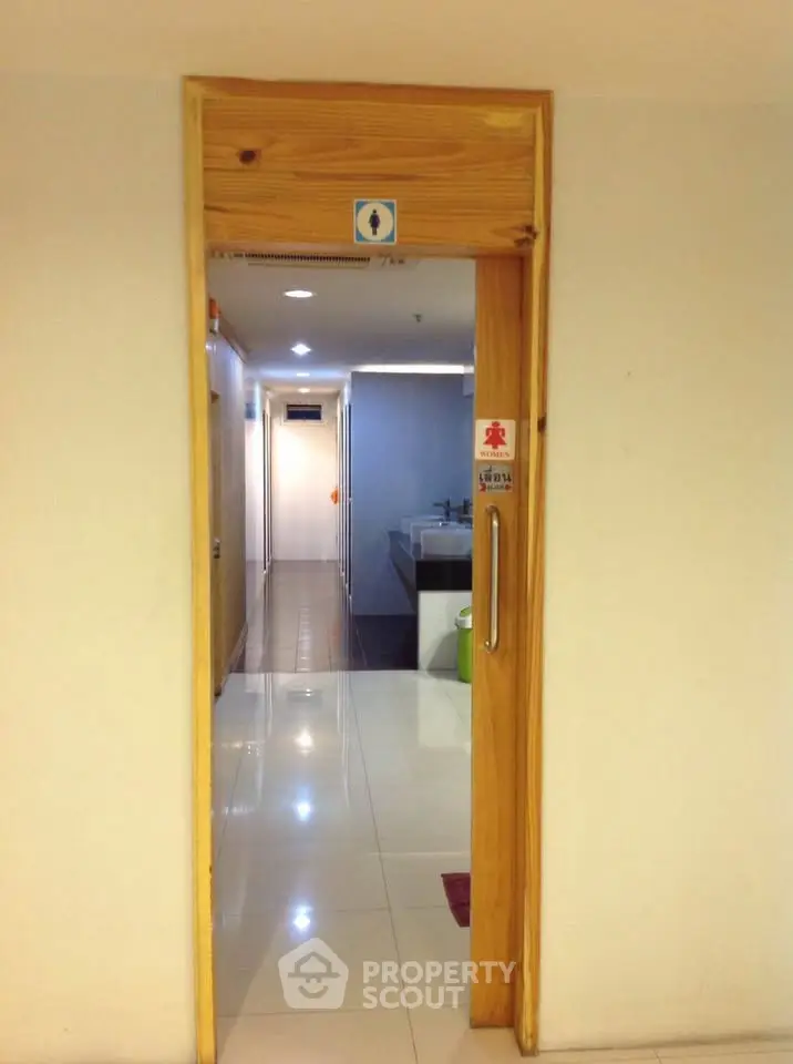 Modern building corridor with restroom entrance and clean tiled flooring.