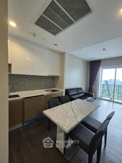 Modern open-layout kitchen and living area with marble dining table and city view balcony.