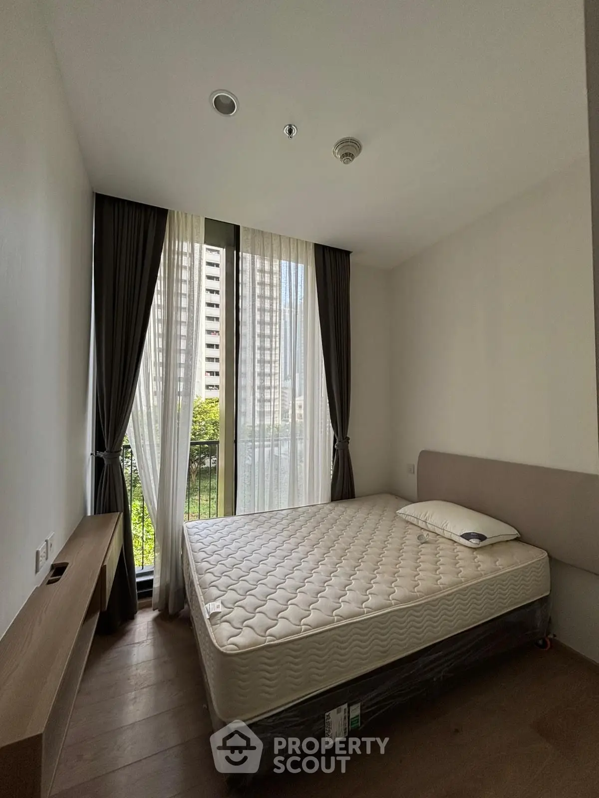 Modern bedroom with large window and minimalist design in urban apartment.