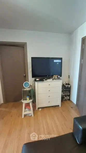 Cozy living room with TV and wooden flooring, perfect for relaxation.