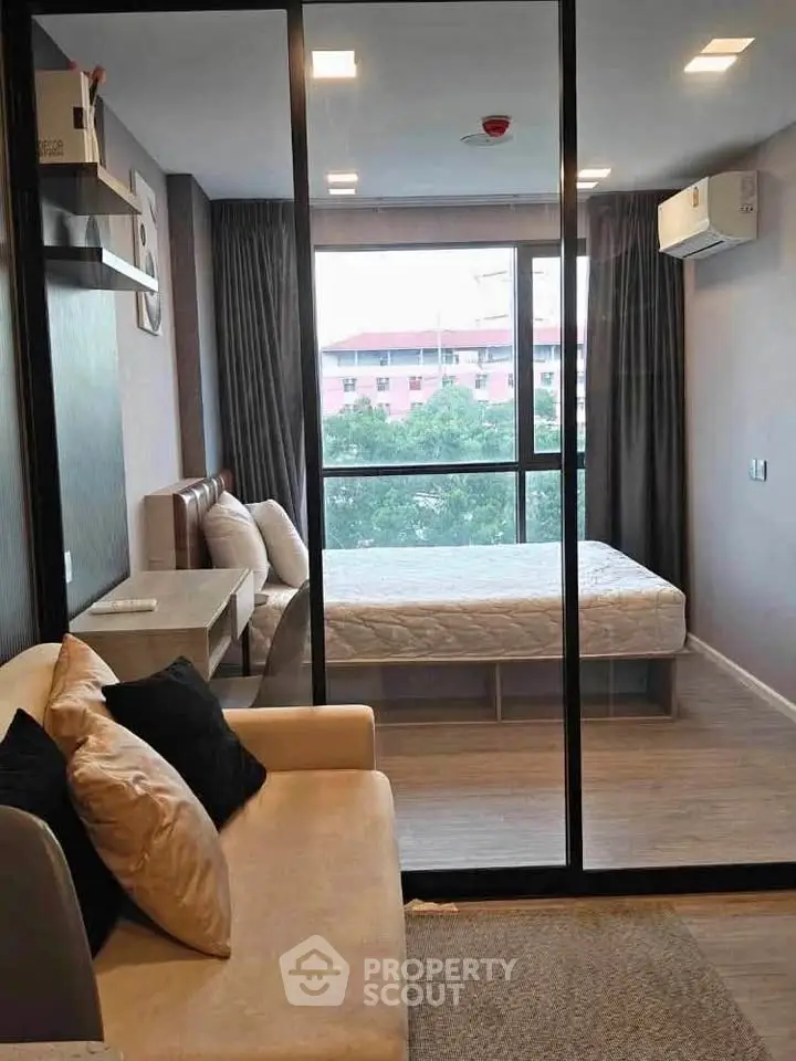 Modern bedroom with glass partition and cozy living area in a stylish apartment.