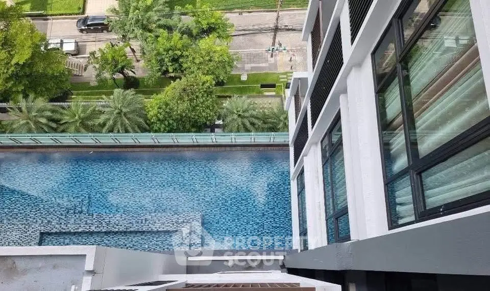 Stunning aerial view of modern building with luxurious pool and lush greenery, perfect for urban living.
