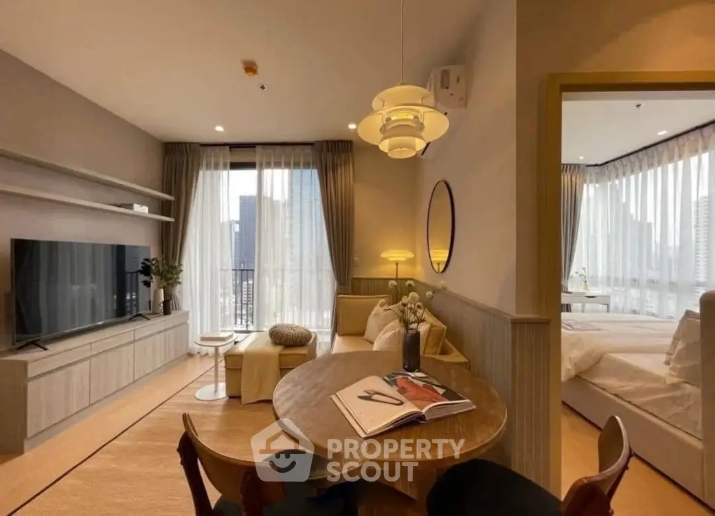 Modern open-plan living room with dining area and bedroom, featuring stylish decor and natural light.
