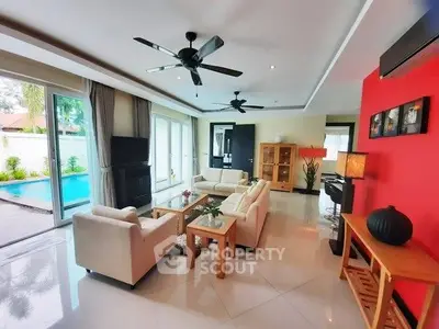 Spacious living room with pool view, modern furniture, and vibrant red accent wall.