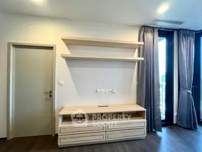 Modern living room with sleek wooden shelves and media console, featuring large windows and elegant curtains.
