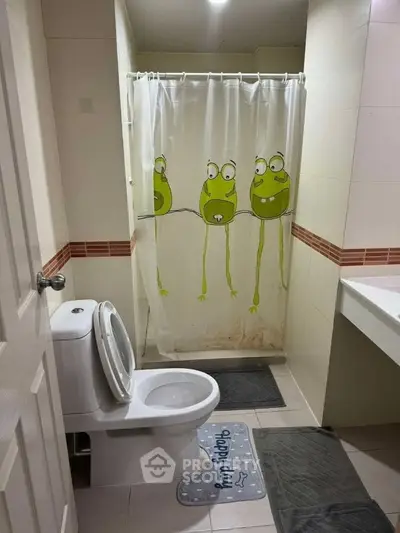 Charming bathroom with playful frog-themed shower curtain and modern fixtures.
