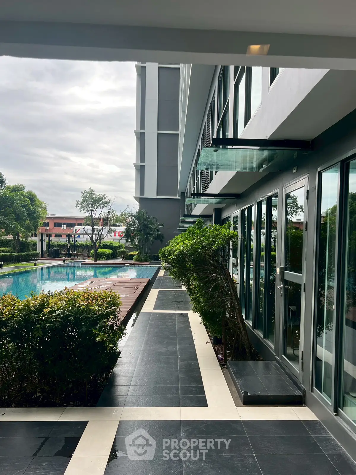 Modern building exterior with poolside view and lush greenery, perfect for luxury living.
