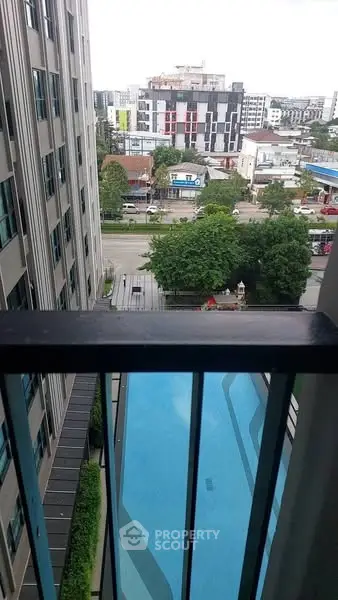 Stunning city view from balcony overlooking a modern pool and urban landscape.