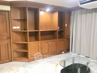 Spacious living room with elegant wooden built-in shelves and modern marble flooring.