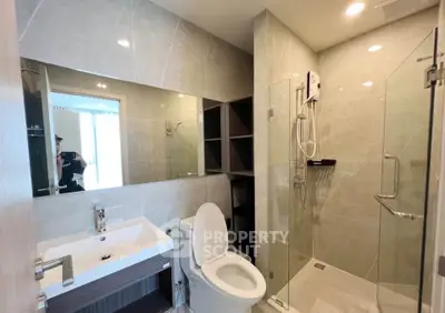 Modern bathroom with glass shower, sleek sink, and elegant tile design.