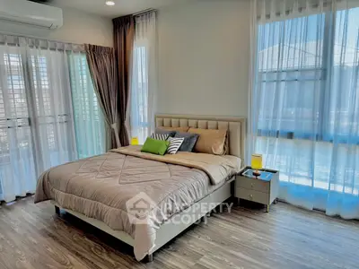 Spacious bedroom with modern decor and large windows for natural light.