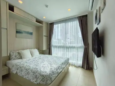Modern bedroom with large window and city view, featuring stylish decor and wall-mounted TV.