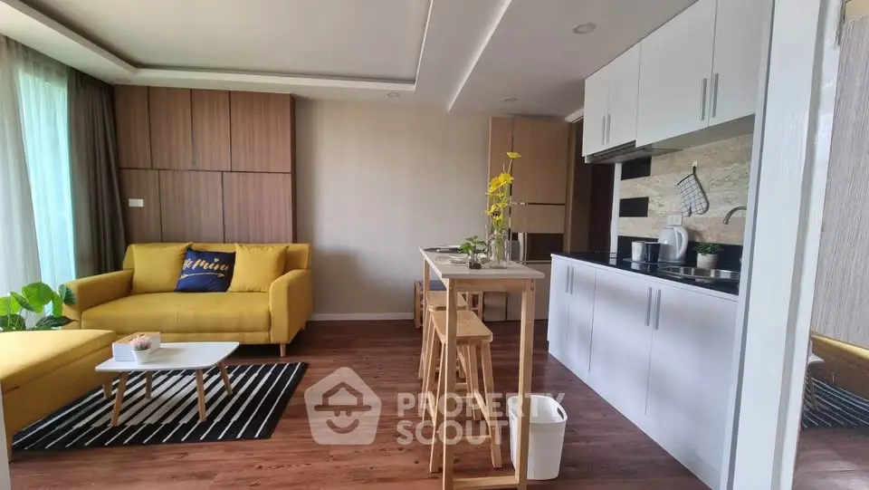 Modern open-layout living room with stylish kitchen and vibrant yellow sofa