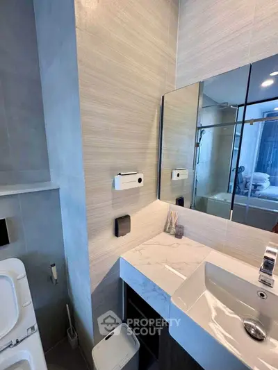 Modern bathroom with sleek design and elegant fixtures, featuring a stylish sink and large mirror.